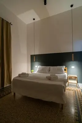 a bedroom with a large white bed with a black headboard at Picciridda Rooms in Palermo