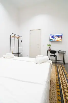 two white beds in a room with a table at Picciridda Rooms in Palermo
