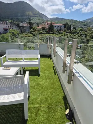 a balcony with white benches and green grass at Panoramica Via Villa in Carini