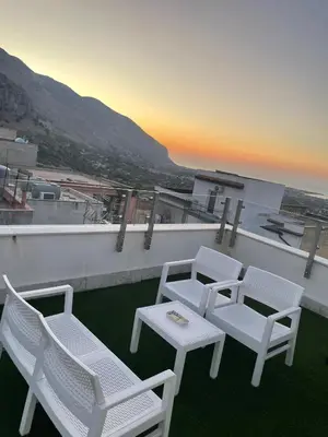 four chairs and a table on a balcony with a sunset at Panoramica Via Villa in Carini