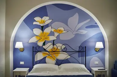 a bedroom with a bed with a blue wall with flowers at Trinacria Caccamo - Luxury Rooms in Caccamo
