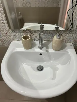 a white bathroom sink with two cups on it at La Cupola - casa vacanze n 10 in Termini Imerese