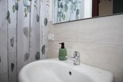 a bathroom sink with a green soap bottle on it at LA CASA DELL'EMIRO in Misilmeri