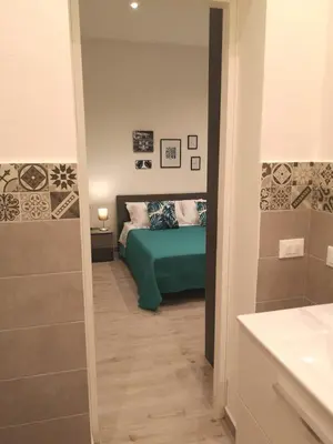 a bedroom with a green bed and a bathroom at Nora’s Home in Palermo