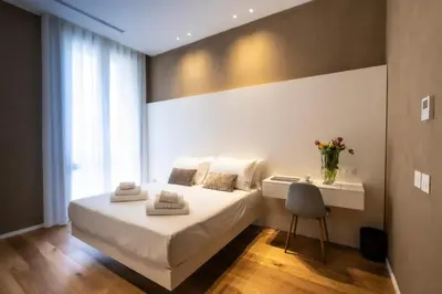 a bedroom with a white bed with a desk and a chair at Amorgiù Luxury Suites in Palermo