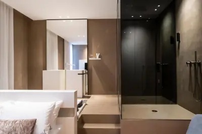 a bathroom with a glass shower and a bed at Amorgiù Luxury Suites in Palermo