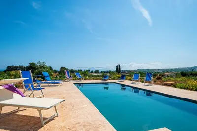 a group of chairs sitting around a swimming pool at Villa Maguetta with private pool in Scopello in Scopello