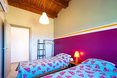 a bedroom with two beds and a purple wall at Villa Maguetta with private pool in Scopello in Scopello