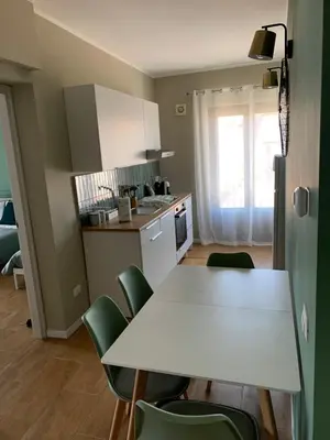 a kitchen with a white table and green chairs at CentruMassimo Apartment in Palermo