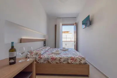 a small bedroom with a bed and a bottle of wine at Un tocco di San Vito in San Vito lo Capo