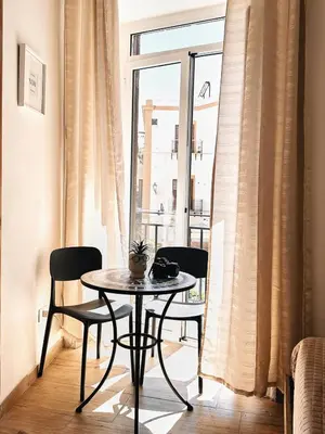 a table and chairs in a room with a window at Monteleone rooms in Palermo