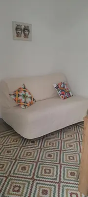 a white couch with two pillows on a carpet at Casa Vacanze Altea in Santa Flavia