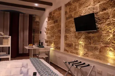 a bedroom with a stone wall with a tv on it at Casuzza palazzo storico, Stazione Centrale Palermo in Palermo