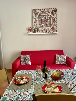 a table with two plates of food and a red couch at Vista sul mare e splendido terrazzo in Castellammare del Golfo