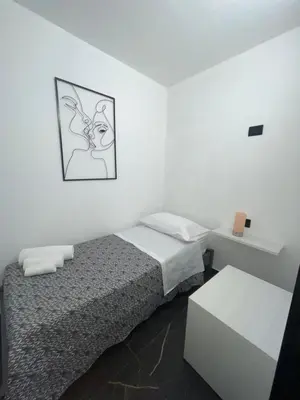 a small white room with a bed and a table at Casa Vacanze Donna Sidora in Palermo