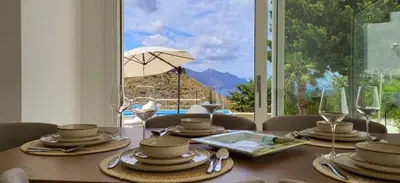 a dining room table with a view of a patio at Villa Ballerina Bianca in Scopello