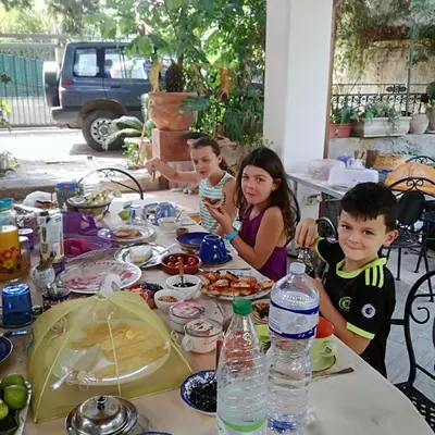 a group of children sitting around a table with food at The Garden in Sferracavallo