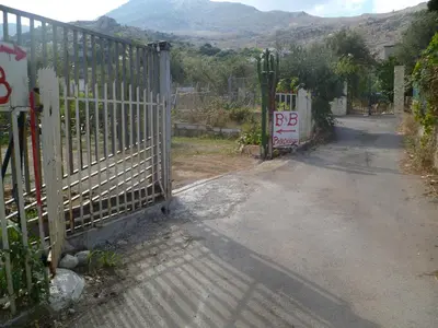 an open gate on a road next to a mountain at The Garden in Sferracavallo