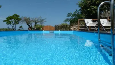 a blue swimming pool with two white chairs in it at VILLA FLAMINIA - con piscina privata in San Vito lo Capo