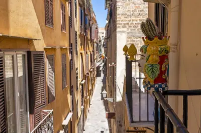 a narrow alley with buildings and a vase on a balcony at Agata & Rosalia 2 Suite Indipendenti e Comunicanti con Balcone & AC in Palermo