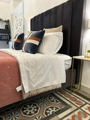 a bed with a black headboard and pillows on it at Maqueda view in Palermo