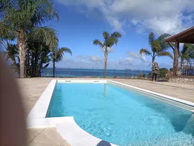 a woman is standing next to a swimming pool at Villa Panorama in Trappeto