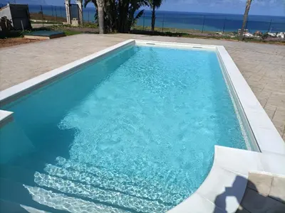 a blue swimming pool with the ocean in the background at Villa Panorama in Trappeto