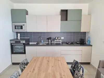 a kitchen with white cabinets and a wooden table at Villini AltaVista in Altavilla Milicia
