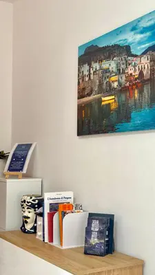 a shelf with books and a painting on a wall at Campofelice Happy Casa in Campofelice di Roccella