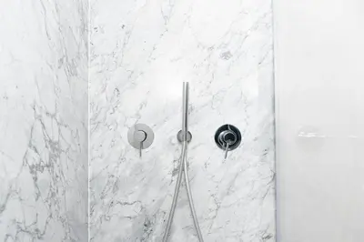 a shower with white marble walls and a shower head at Massim'home in Palermo