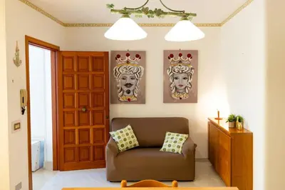 a living room with a brown couch and two masks at Calasole House: Mare a 2 Passi in San Vito lo Capo