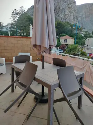 a table and chairs with an umbrella on a patio at La Casa di Anna, Mondello in Palermo