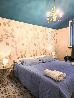 a bedroom with a bed with a blue comforter at CasaRò (delizioso alloggio a Mondello) in Palermo