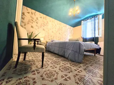 a bedroom with a bed and a chair and a chandelier at CasaRò (delizioso alloggio a Mondello) in Palermo