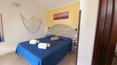 a bedroom with a blue bed with towels on it at Alykè Appartamenti Vacanze Macari in Macari