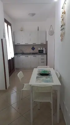 a kitchen with a white table and chairs in a room at Alykè Appartamenti Vacanze Macari in Macari