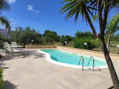 a swimming pool with a palm tree next to it at Villa Donna Franca con piscina privata in Castellammare del Golfo