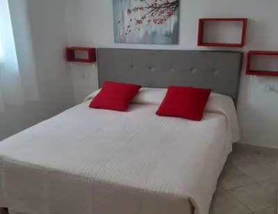 a bedroom with a bed with two red pillows on it at Villa Donna Franca con piscina privata in Castellammare del Golfo
