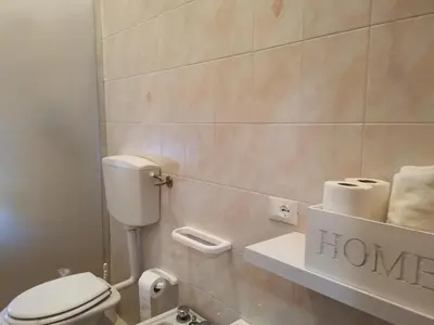 a bathroom with a toilet and towels on a shelf at La Vie Est Belle in Balestrate