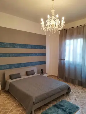 a bedroom with a large bed and a chandelier at La Vie Est Belle in Balestrate