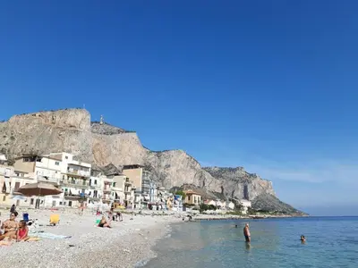 a group of people on a beach with houses at L'ancora casa vacanze in Palermo