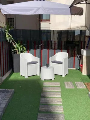 a patio with two white chairs and an umbrella at Zisa Private House in Palermo
