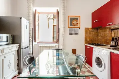 a kitchen with a glass table and red cabinets at Dimora degli Scalzi - Dive into Palermo's History in Palermo