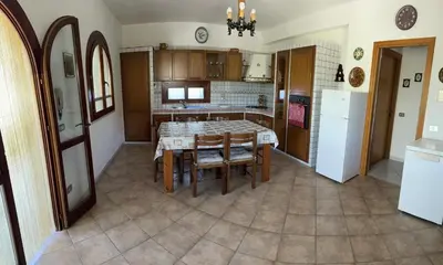 a kitchen with a table and a kitchen with a refrigerator at Villa Il Giardino di Rosa- 5 Min from the sea-Fraginesi in Castellammare del Golfo
