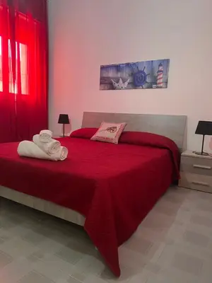 a bedroom with a red bed with towels on it at Miramare in Balestrate