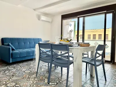 a dining room with a table and chairs and a blue couch at M'AMA apartment 2 in Ficarazzi