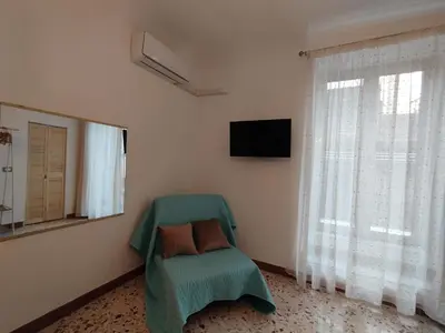 a room with a green chair and a television at Le due Marie in Palermo