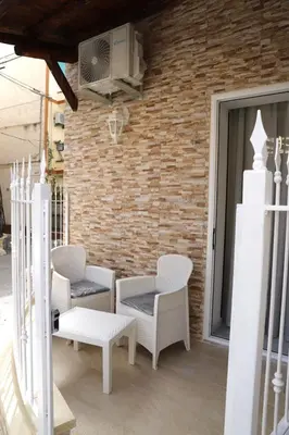 a patio with white chairs and a brick wall at Lo scarrozzo room in Palermo