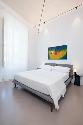 a white bedroom with a large bed with white sheets at Piano Alloro in Palermo