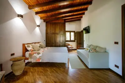 a bedroom with a white bed and a couch at Baglio Sammartano ROOM&TOUR in Castelluzzo